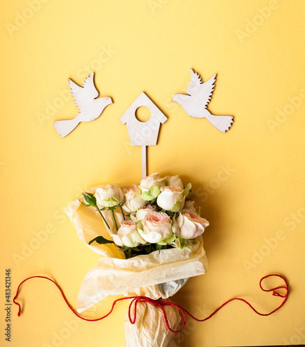 love wedding  housewarming composition with birdhouse,birds figurines and a bouquet of white roses on the yellow background