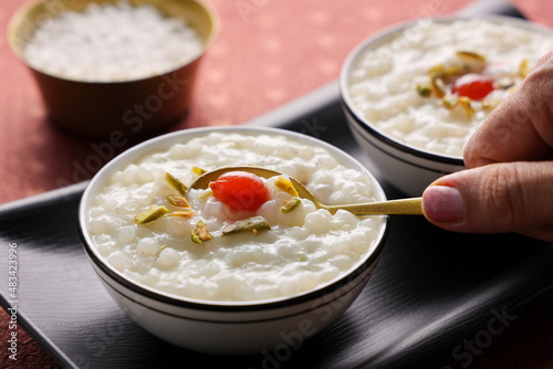 Sabudana Kheer thick pudding with tapioca pearls sago dessert cassava root woman hand serving eating Indian sweet mithai  chowari payasam for Mahashivratri Ram Navami Diwali festival.