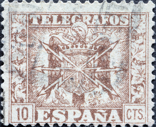 Spain - circa 1940: a postage stamp from Spain, showing a coat of arms with lightning bolts for telegraph and telephone
