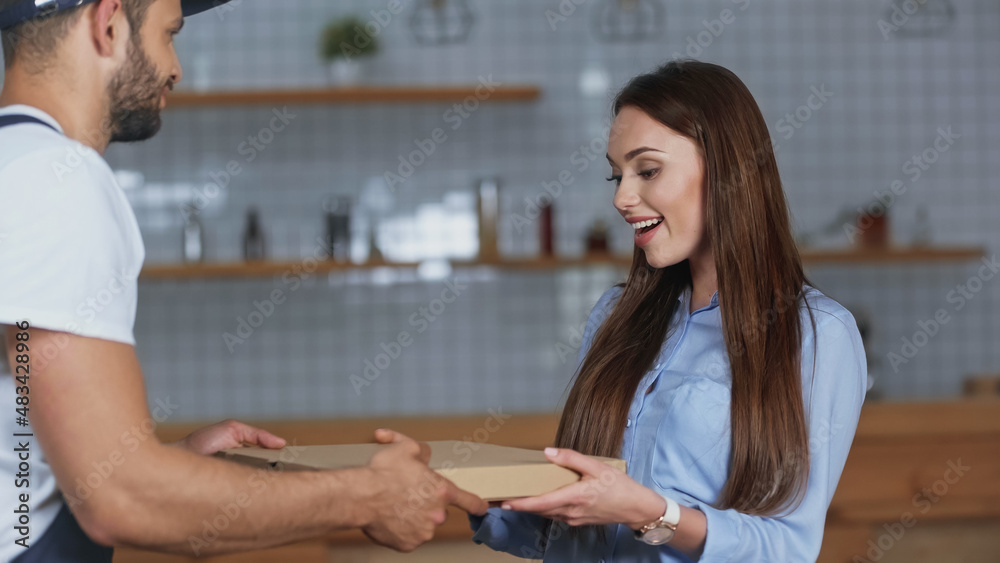 Smiling woman taking pizza box from courier at home