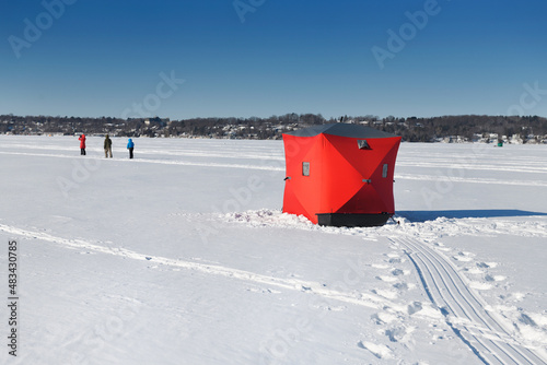 Family hiking on frozen lake and red ice fishing tent on Kempenfelt Bay of Lake Simcoe in winter Barrie Ontario Canada photo