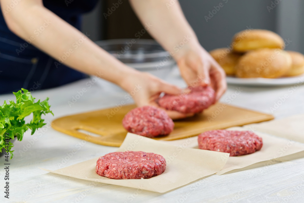 Woman's hand forming a beef meat for a hamburger party. Portioning ground meat. Homemade burgers. Making food at home. close up