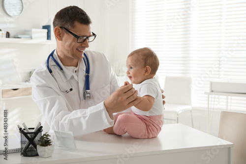 Pediatrician examining cute little baby in clinic. Space for text photo