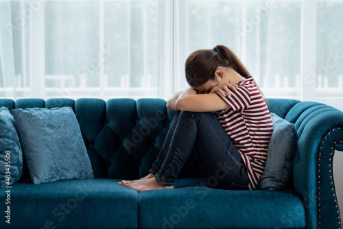 Sad and depressed Asian women sitting on couch at home © surachetkhamsuk