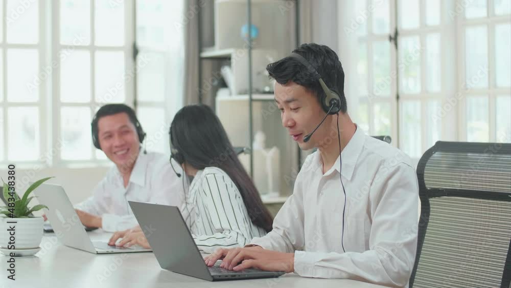 A Man Of Three Asian Call Center Agents Wearing Headset And Speaking To Customers On The Call While Two Of His Colleagues Are Talking With Each Other During Working At The Office
A Man Of Three Asian Call Center Agents Wearing Headset And Speaking To Customers On The Call While Two Of His Colleagues Are Talking With Each Other During Working At The Office