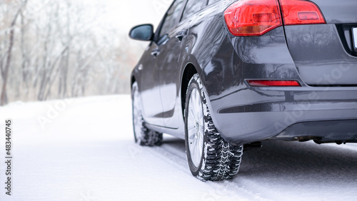 Car on the Winter Road. Close-up Image of Winter Car Tire on the Snowy Road. Safe Driving Concept.