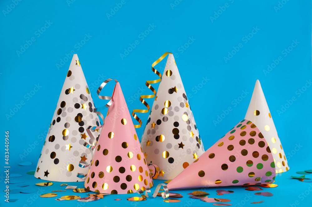 Colorful party hats and confetti on light blue background Colorful party hats and confetti on light blue background