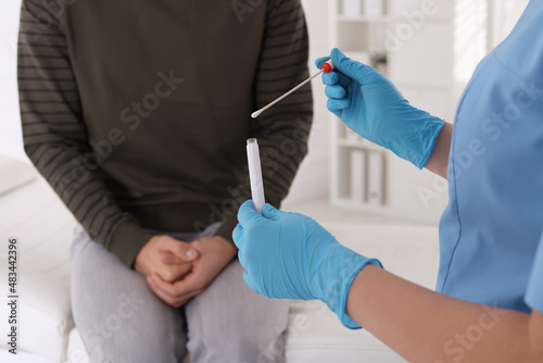 Doctor taking sample for STD testing from man in clinic, closeup photo