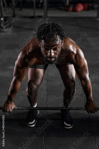 Confident muscular afro american man training squats with barbells at gym. professional black fit bodybuilder workout with barbell, weightlifting. portrait. workout, sport, fitness concept