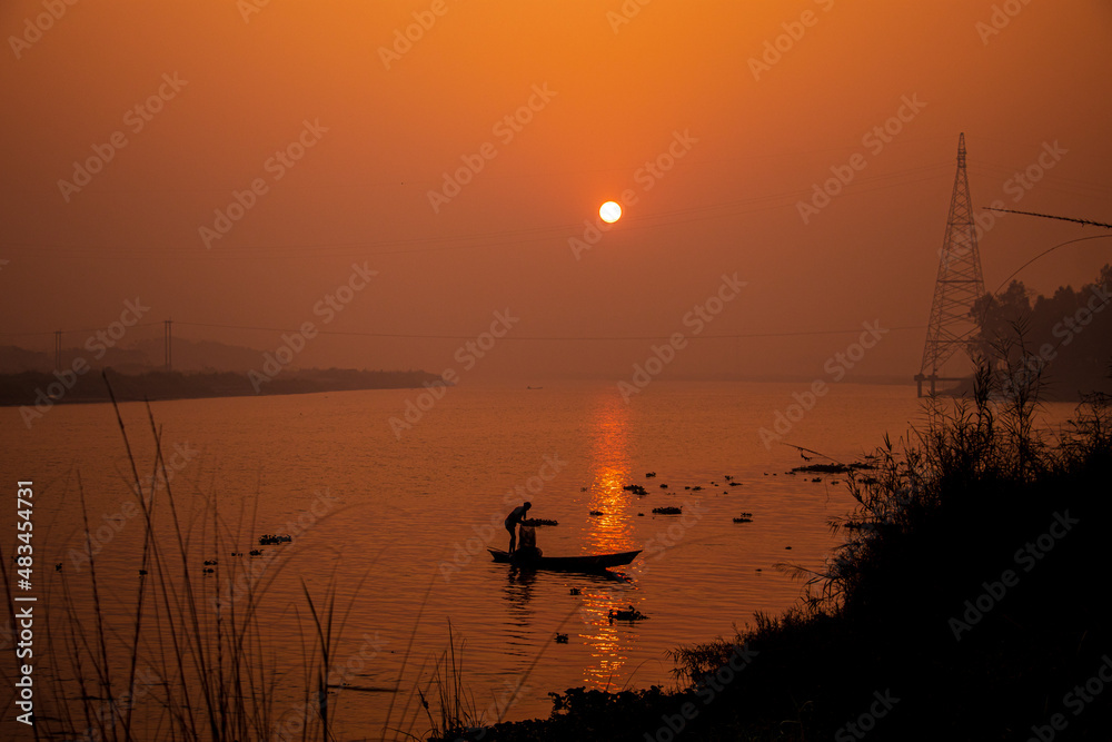 A fisherman fishing by the boat in the misty winter morning. I captured this image on January 17, 2022, from Bangladesh, South Asia