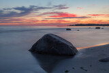 Beautiful colorful sunset at the sea with dramatic clouds. Rocky shore of the Baltic sea.