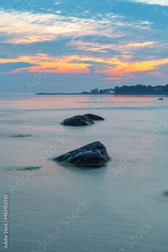 Blue hour after the sunset over rocky Baltic sea cost. Small stones and big boulders in the sea. Long exposure