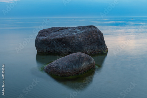 Blue hour after the sunset over rocky Baltic sea cost. Small stones and big boulders in the sea. Long exposure