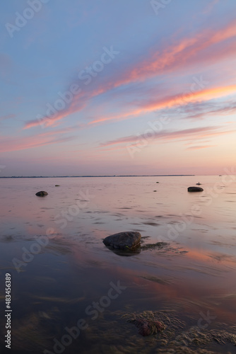 Sunset with a beutiful pink colored clouds. Long exposure photo of rocky sea shore in the evening