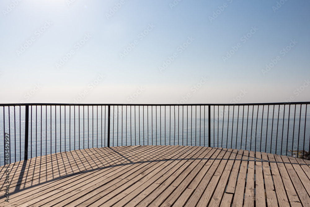 Obraz premium Beautiful wooden terrace with a metal fence is on the beach by the blue sea