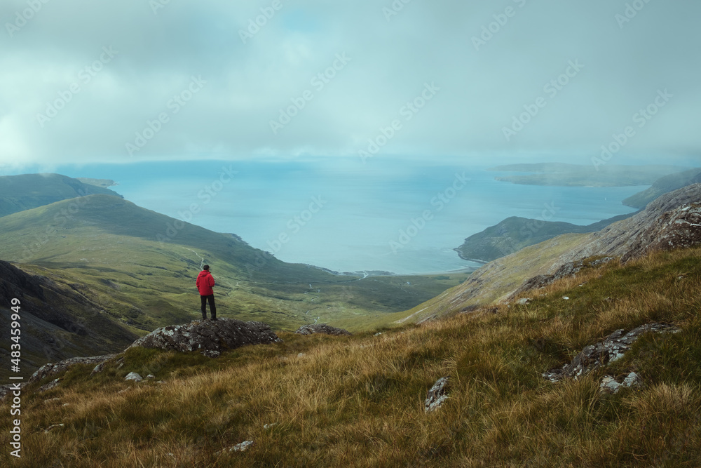 A hiker at the top of the mountain views the magnificent landscape of the sea bay. Isle of Skye. Bla Bheinn, Isle of Skye, Scotland 