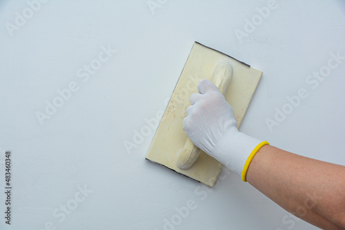 plastering man hand sanding the plaster in white wall