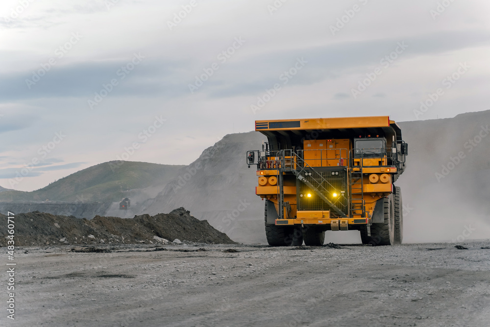 A dump truck drives through an open pit. A dump truck drives through an open pit.