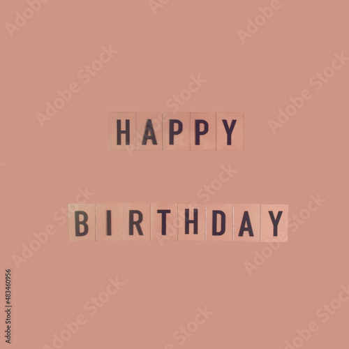 Happy Birthday on pastel deco peach background. Minimal party layout.