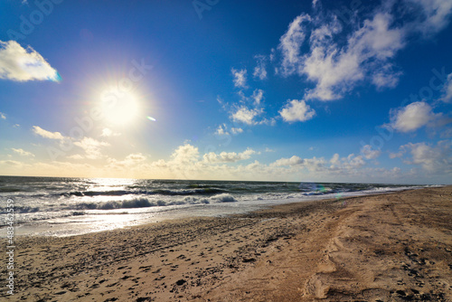 Panoramic view of Baltic sea from sandy shore, sand dunes. Dramatic sky with glowing clouds, sunbeams. Denmark