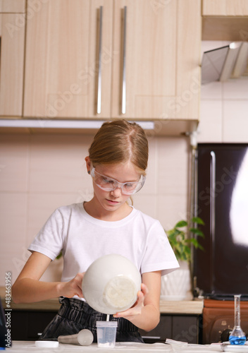 the girl is preparing for a chemical experiment in a home laboratory.