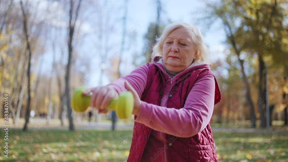 Senior woman lifting a dumbbell slowly, training arm muscles after injury Senior woman lifting a dumbbell slowly, training arm muscles after injury