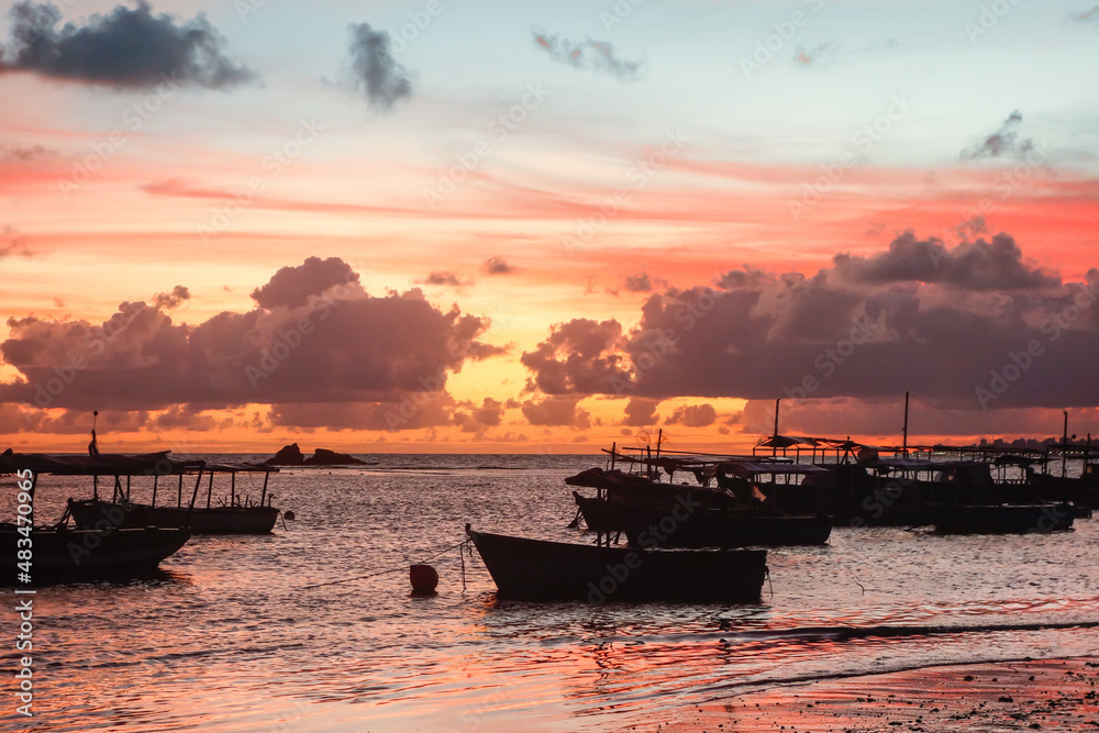 Silhouette Of Boats Moored In The Tropical Beach At colored Sunset.
