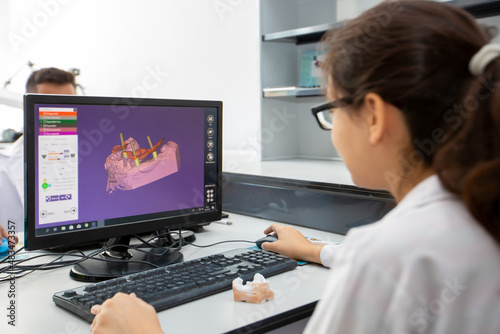Person working on computer with dental software platform for make dental prosthesis photo