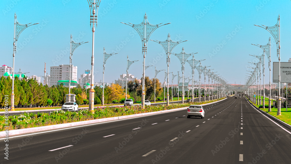 Urban city scape of Ashgabat city center with wide highway and light traffic. High white marble buildings by sides. Capital of Turkmenistan. Central Asia.