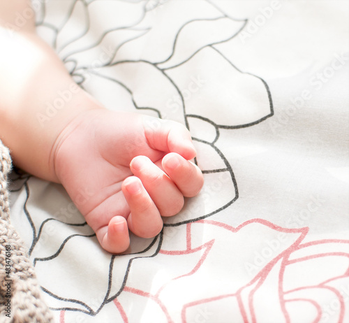 The baby's hand lies on the bed close-up