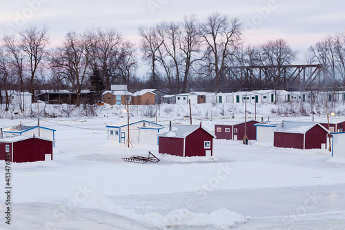 Atlantic tomcod ice fishing cabins set on a frozen river with others on the banks in the background, Sainte-Anne-de-la-Pérade, Quebec, Canada photo