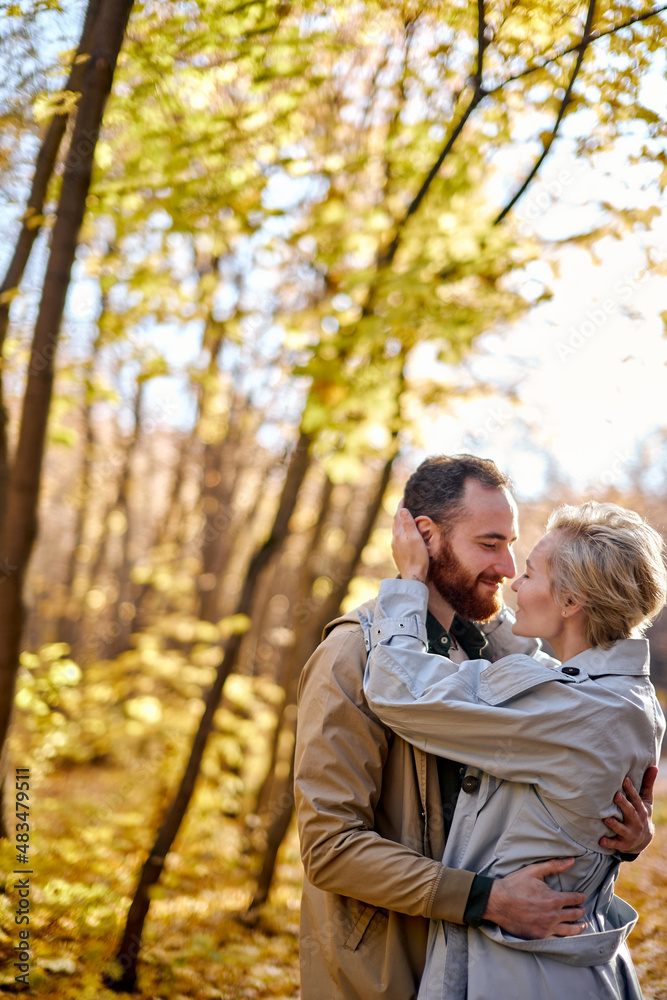 lovely couple hugging with love in the middle of park or forest during autumn at sunny day, caucasian man and woman in coats feel tenderness to each other, good relationships concept lovely couple hugging with love in the middle of park or forest during autumn at sunny day, caucasian man and woman in coats feel tenderness to each other, good relationships concept