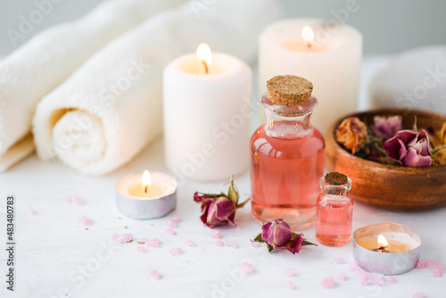 Concept of spa treatment in salon. Natural organic oil  towel  candles as decor. Atmosphere of relax  serenity and pleasure. Anti-stress and detox procedure. Luxury lifestyle. White wooden background