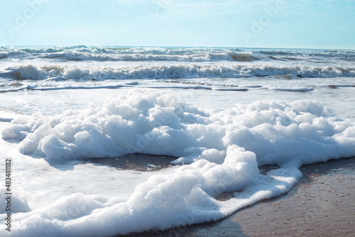Thick sea foam on the sandy shore. Coastal cappuccino is a natural phenomenon, sea pollutio © Natalia