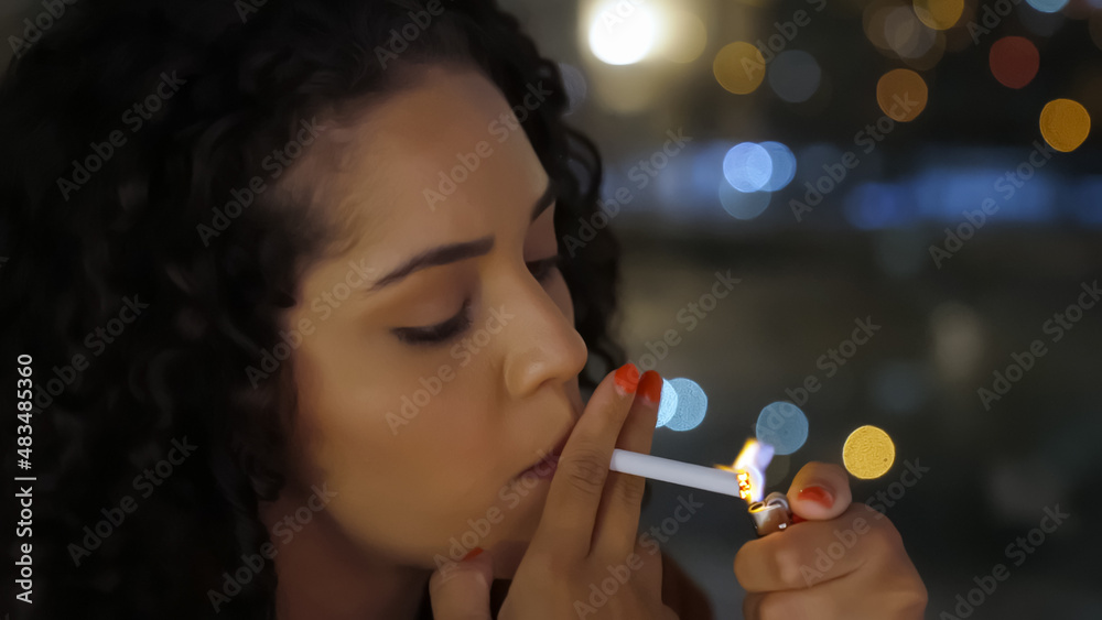 Fototapeta premium A sad Latin girl smokes late at night.