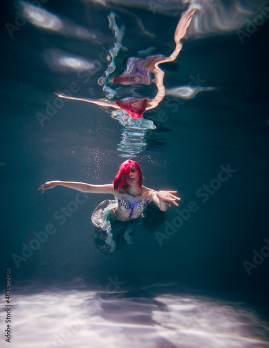 Young woman underwater in a beautiful dress underwater shooting © Helen