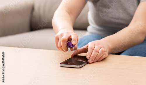 Cropped shot of an unrecognizable woman cleaning her device or phone screen at home