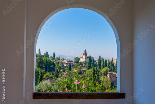 The alhambra through the arched window from the generalife gardens in granada, spain