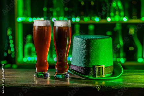 Tall glasses of cold beer, ale on the bar counter. Holiday of Ireland on St. Patrick's Day in irish pub, bar. Festive Leprikon's green hat. National tradition of carnival celebrating March 17