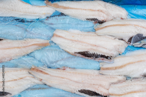 frozen fish Longtail hake in a box. Packaging with interleave plastic film and fish. Argentine tradel fish, after primary processing on a trawler, is ready for sale photo