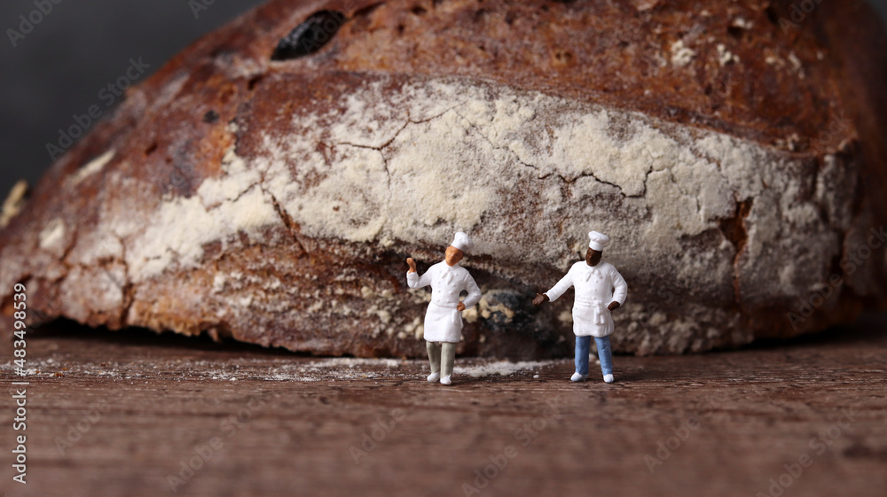 Obraz premium Roasted bread and two miniature chefs. Miniature people and business concept. 