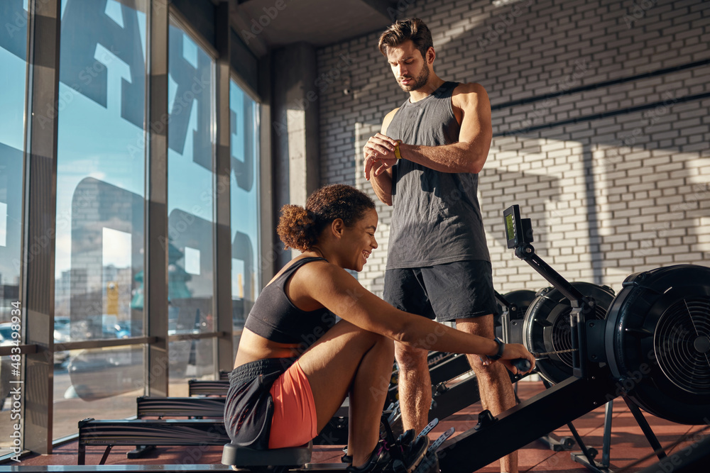 Trainer look time on wristwatch and girl exercise