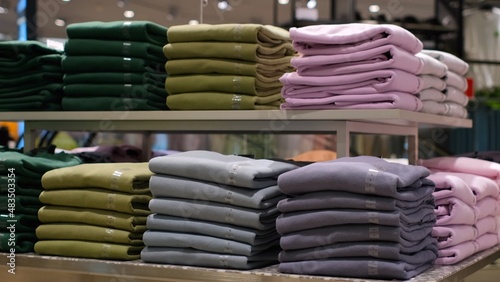  Colorful arrangement of folded clothing on the fashion store shelf in a shopping mall, buying t-shirts and long sleeves 
