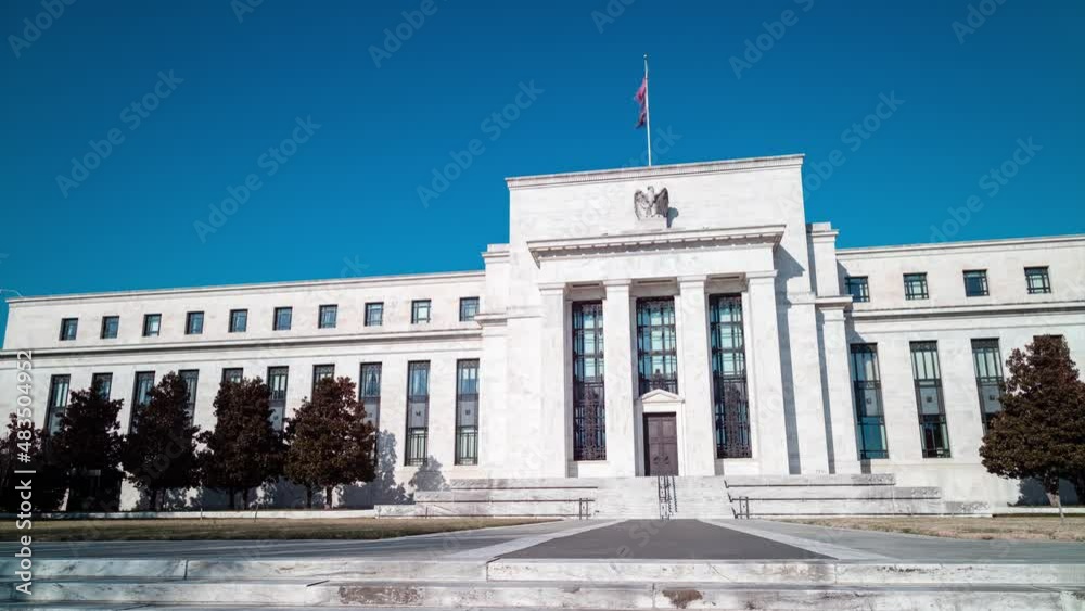 A daytime time-lapse of the Marriner S. Eccles Federal Reserve Board Building in Washington, D.C. on a sunny winter day. The camera pans from left to right.