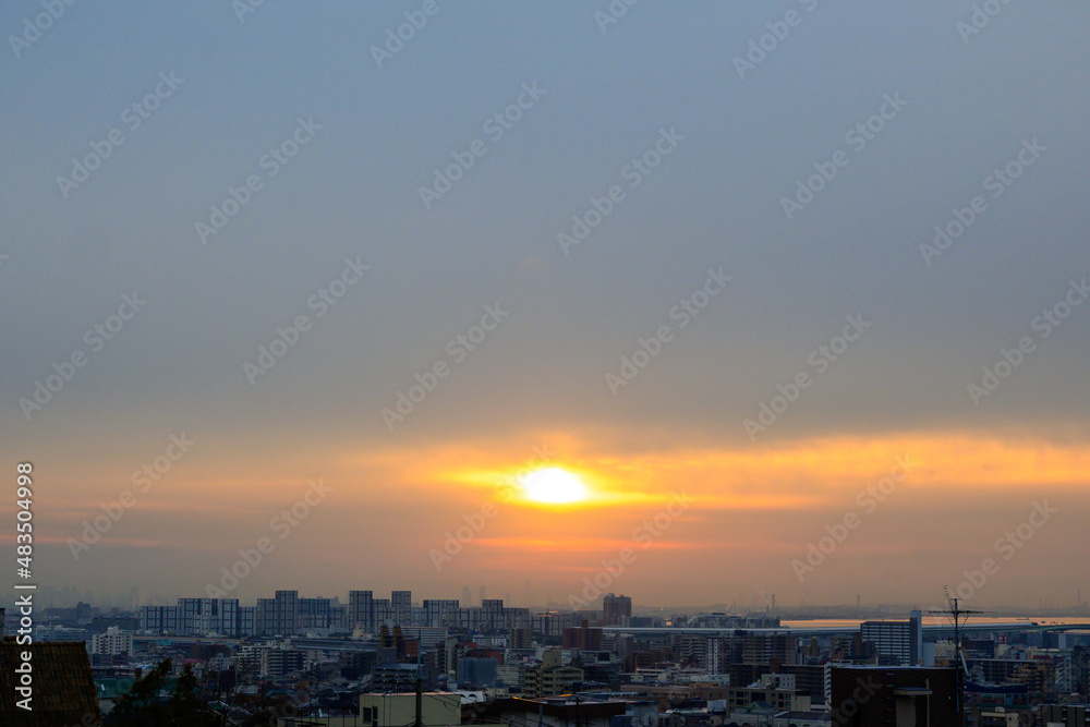 早朝、朝日にキラキラ輝き、黄金色に輝く海。兵庫県芦屋市芦屋浜より大阪湾を臨む。遠くに大阪南港のビルが見える