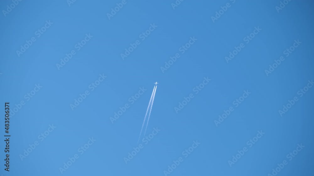 Distant passenger jet plane flying on high altitude on clear blue sky leaving white smoke trace of contrail behind. Air transportation concept Distant passenger jet plane flying on high altitude on clear blue sky leaving white smoke trace of contrail behind. Air transportation concept