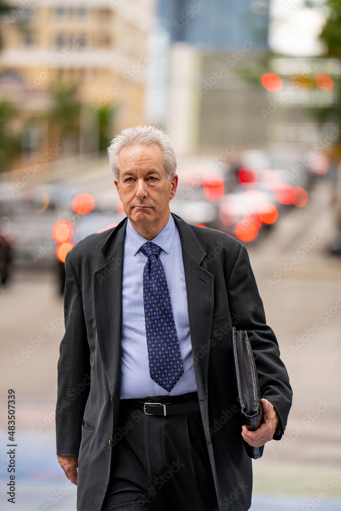 Photo of a mature old businessman crossing the street