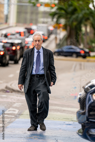 Photo of a mature old businessman crossing the street