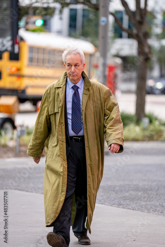 Canvas Print Businessman with an oversize trenchcoat walking in the city