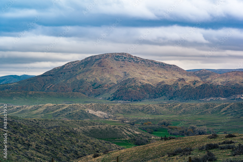 Fototapeta premium landscape of mountain range on top of green hillside with cloudy sky in Wyoming